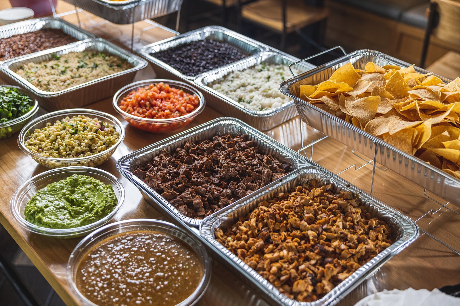 DosBros catering spread with steak, chicken, guacamole, rice, beans and chips